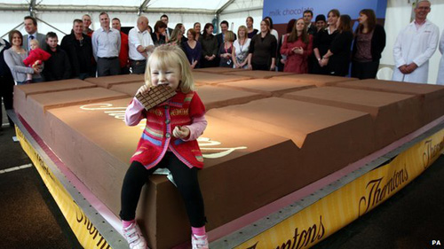 a girl eating chocolate on a big chocolate bar